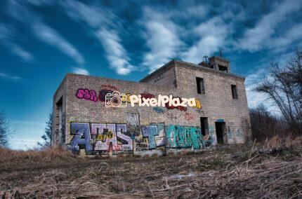 Abandoned Brick Building with Graffiti under Dramatic Sky